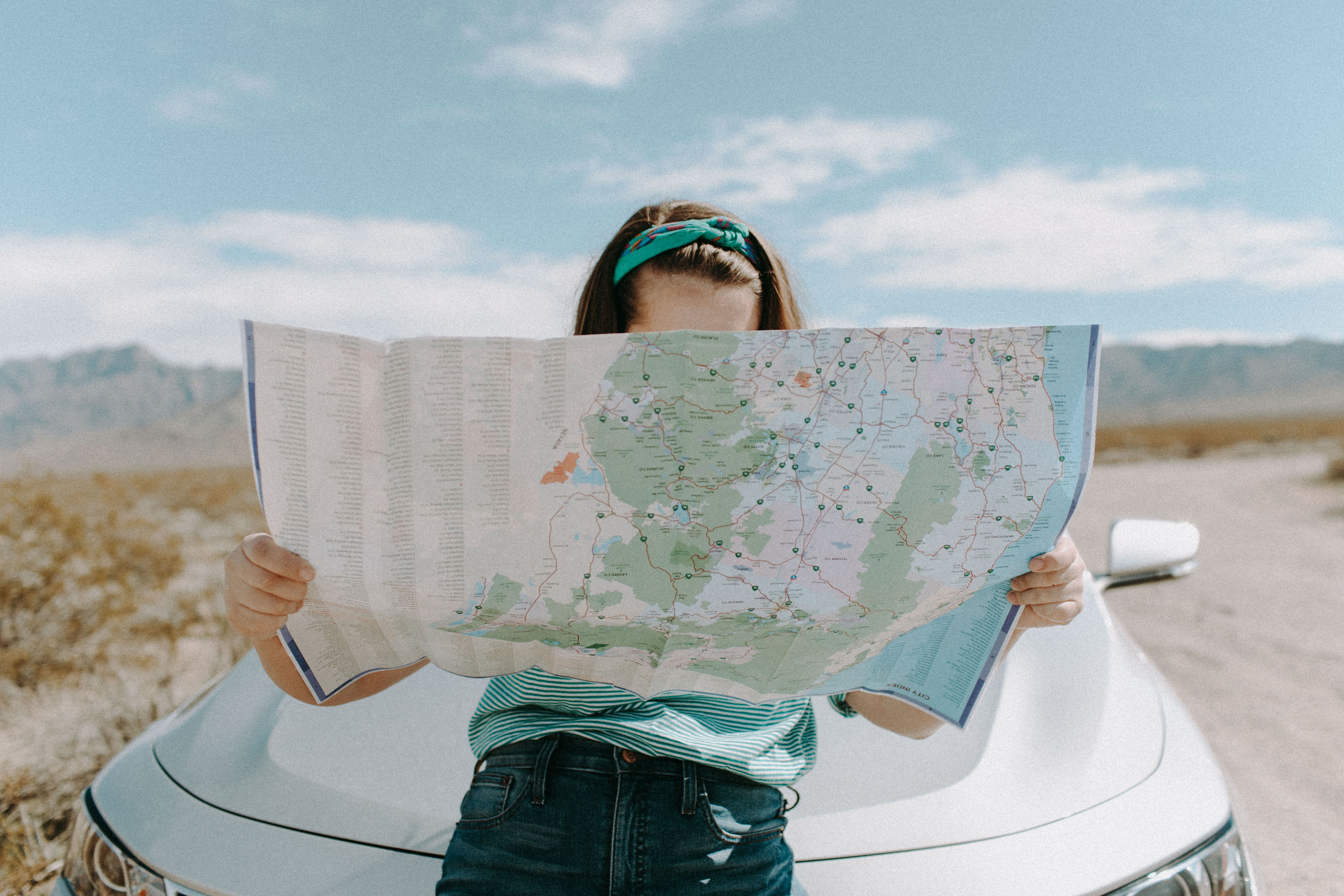 A woman holds a map while traveling through the scenic desert of California, USA. — Foto: Leah Newhouse / Pexels