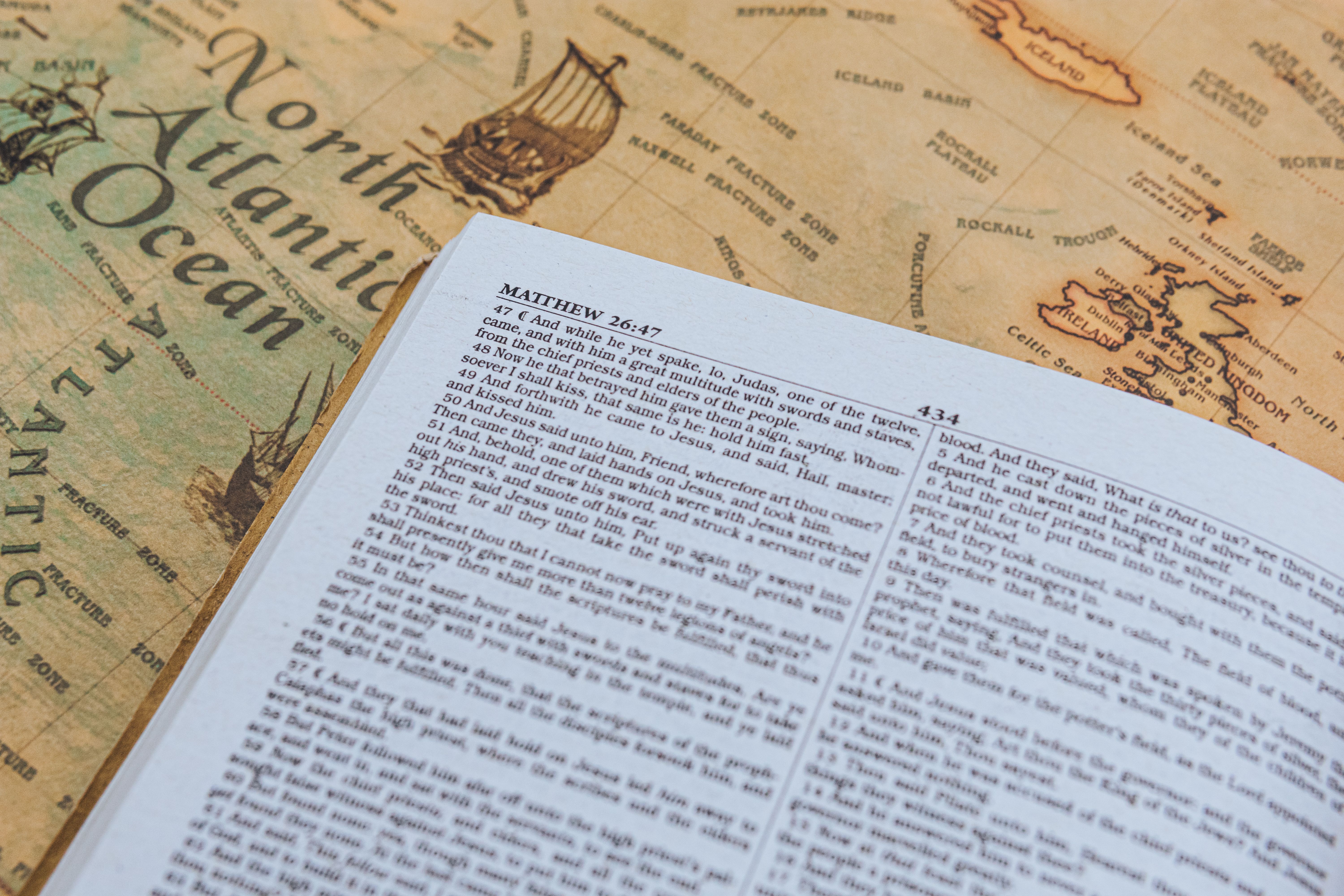 Open Bible with text from Matthew 26:47 on vintage map of North Atlantic Ocean. — Foto: Nothing Ahead / Pexels